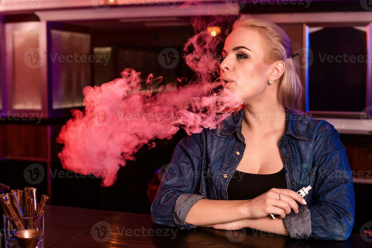 giovane bella donna Fumo un elettronico sigaretta a il Vape bar foto