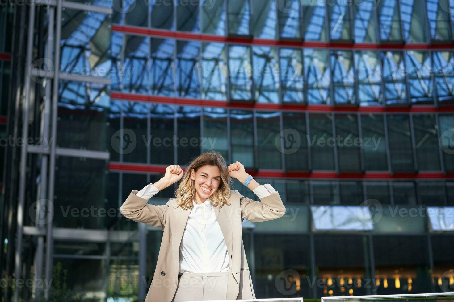 eccitato giovane donna d'affari festeggiare, trionfante, sensazione gratuito e felice, in posa nel il città vicino ufficio edifici foto