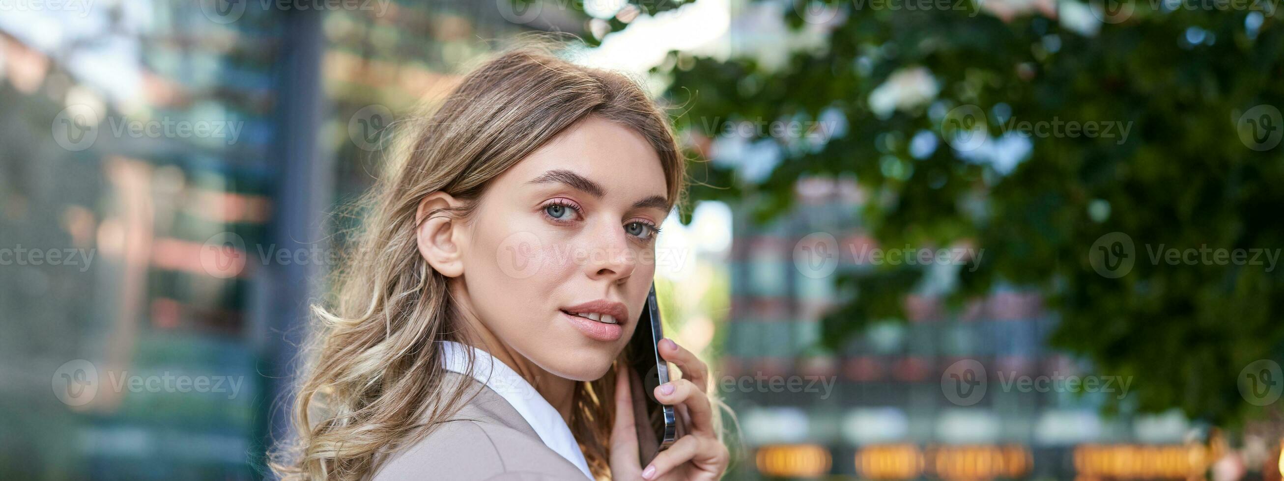 vicino su tiro di donna d'affari parlando su mobile Telefono. aziendale donna chiamata qualcuno, guardare intorno a, in piedi all'aperto foto