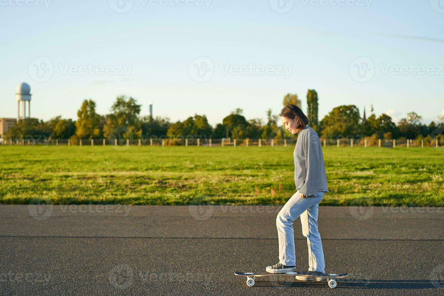 Hobby e stile di vita. giovane donna equitazione skateboard. pattinatore ragazza godendo crociera su longboard su soleggiato giorno all'aperto foto
