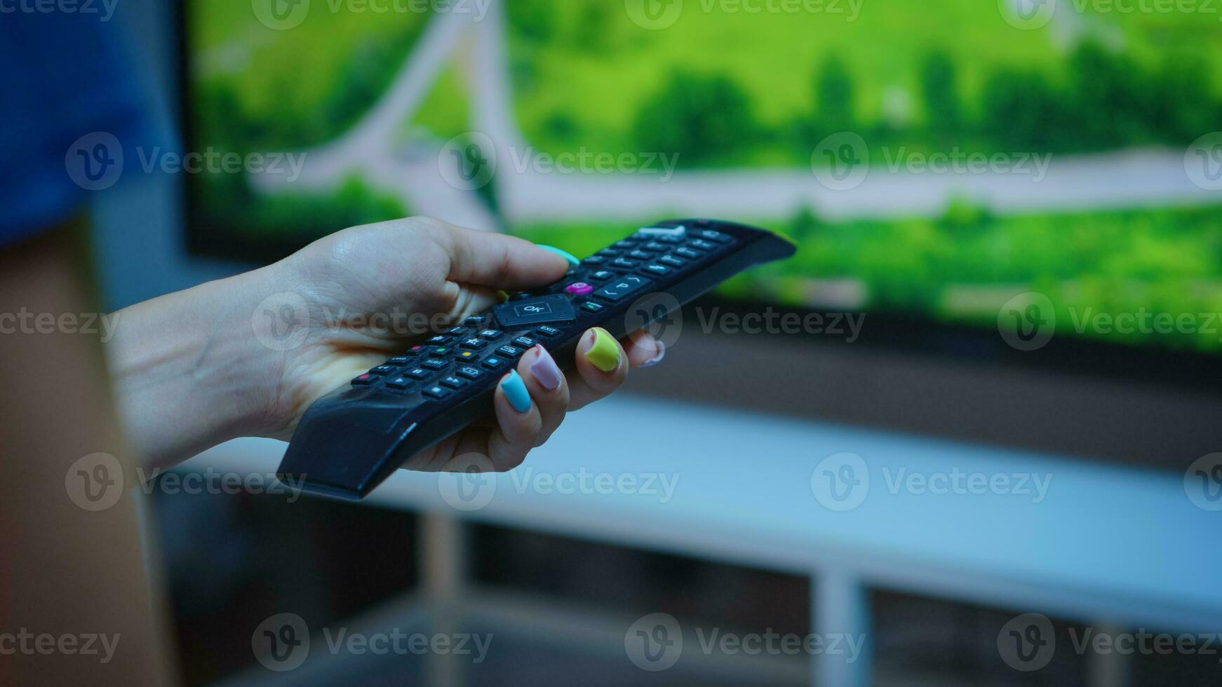 signora Tenere tv a distanza controllo e urgente il pulsante. vicino su di donna mano mutevole tv canali seduta su confortevole divano nel davanti di televisione utilizzando controllore per la scelta un' film foto