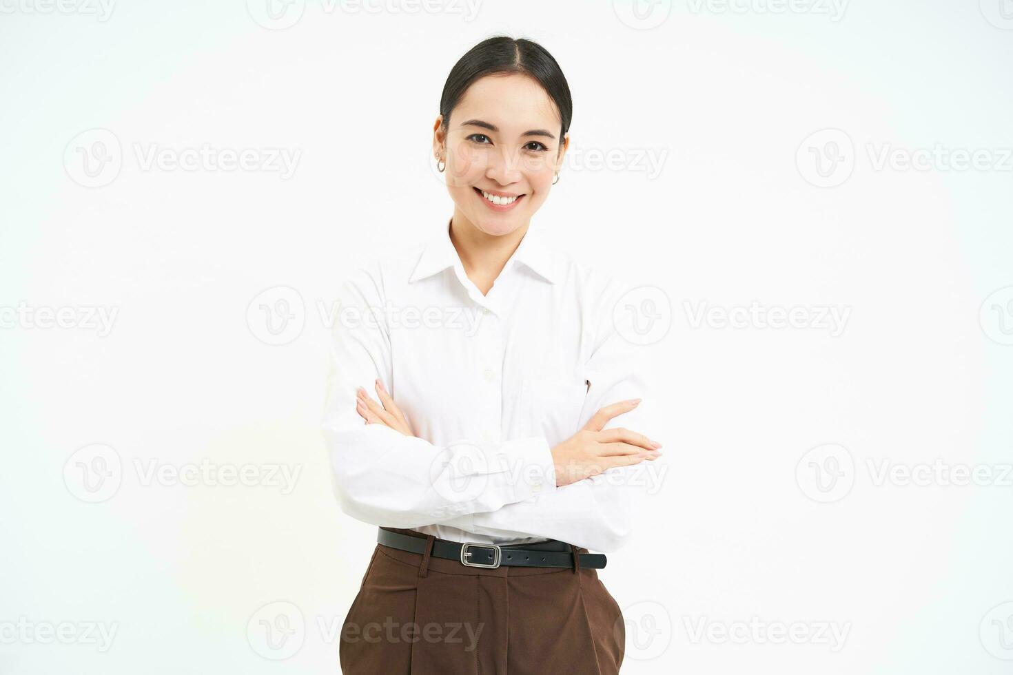 fiducioso femmina gestore, asiatico commessa detiene braccia attraversato con professionale Guarda, bianca sfondo foto