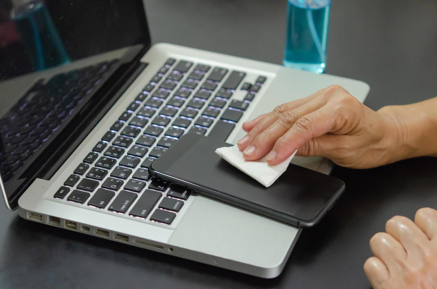 pulire e disinfettare il telefono cellulare con alcool. concetto di assistenza sanitaria foto