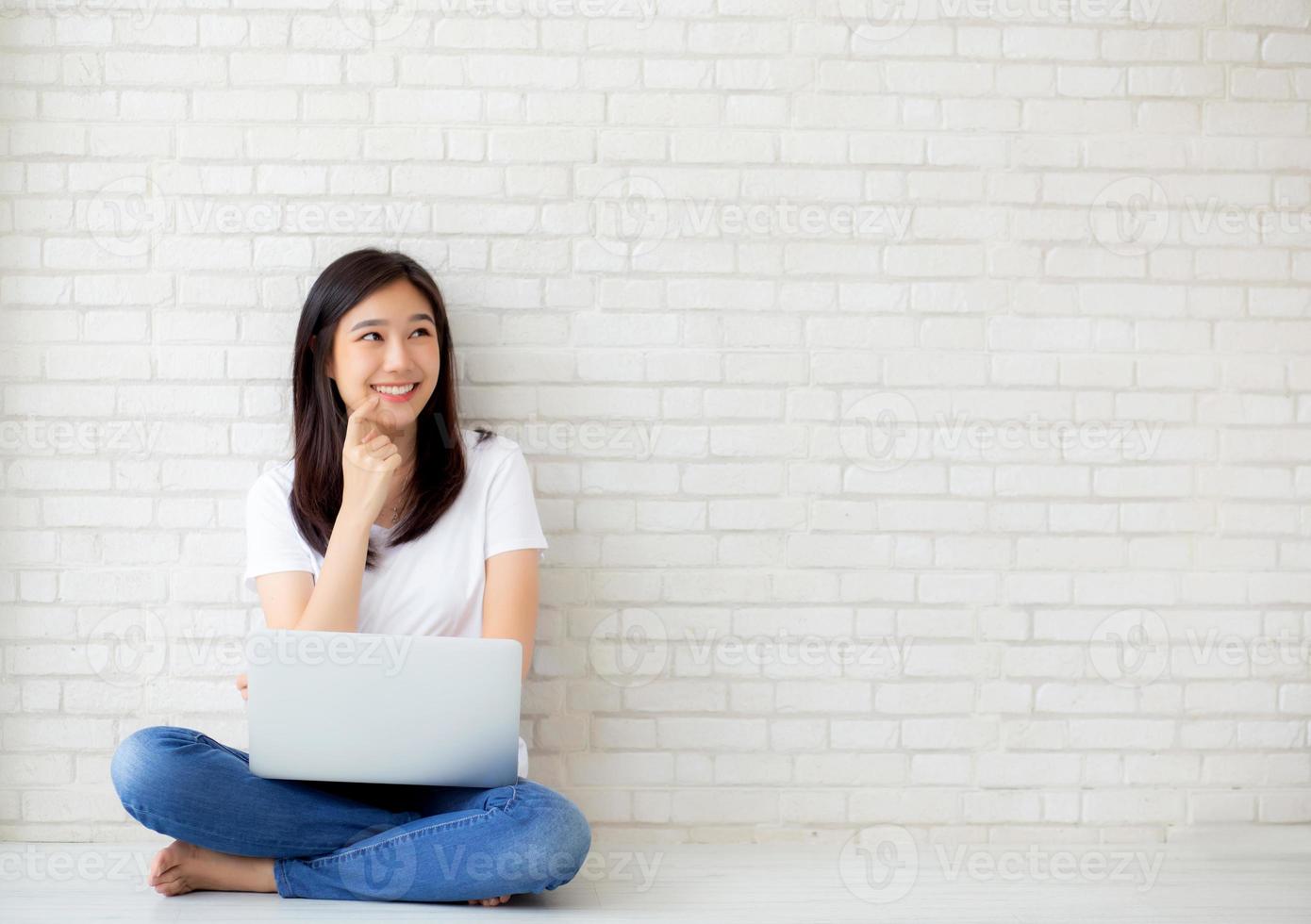 giovane donna asiatica che lavora al computer portatile e pensa. foto