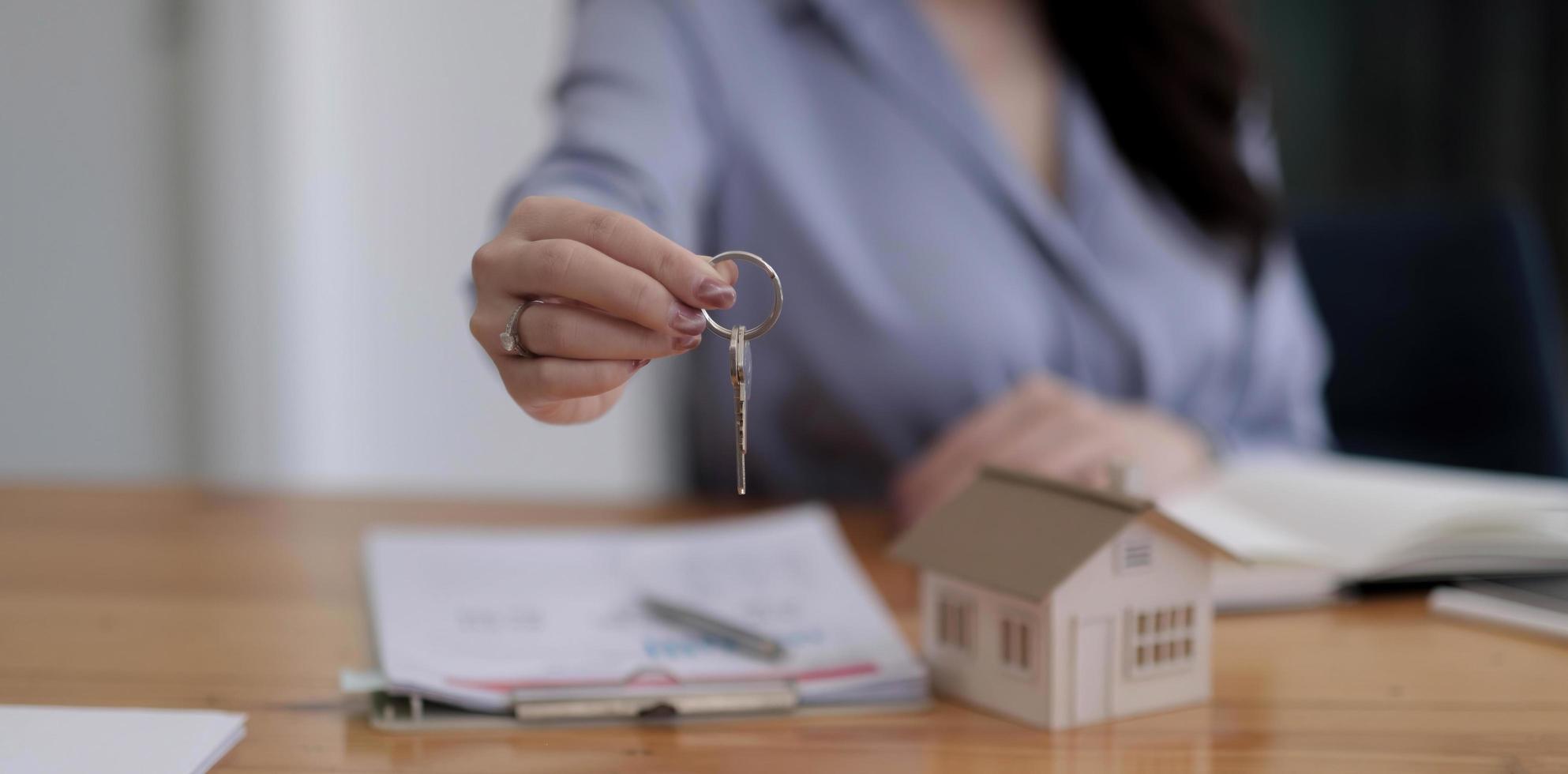 chiave di casa nella protezione della mano dell'agente del broker assicurativo della casa o nella persona del venditore che dà al proprietario del cliente dell'acquirente foto