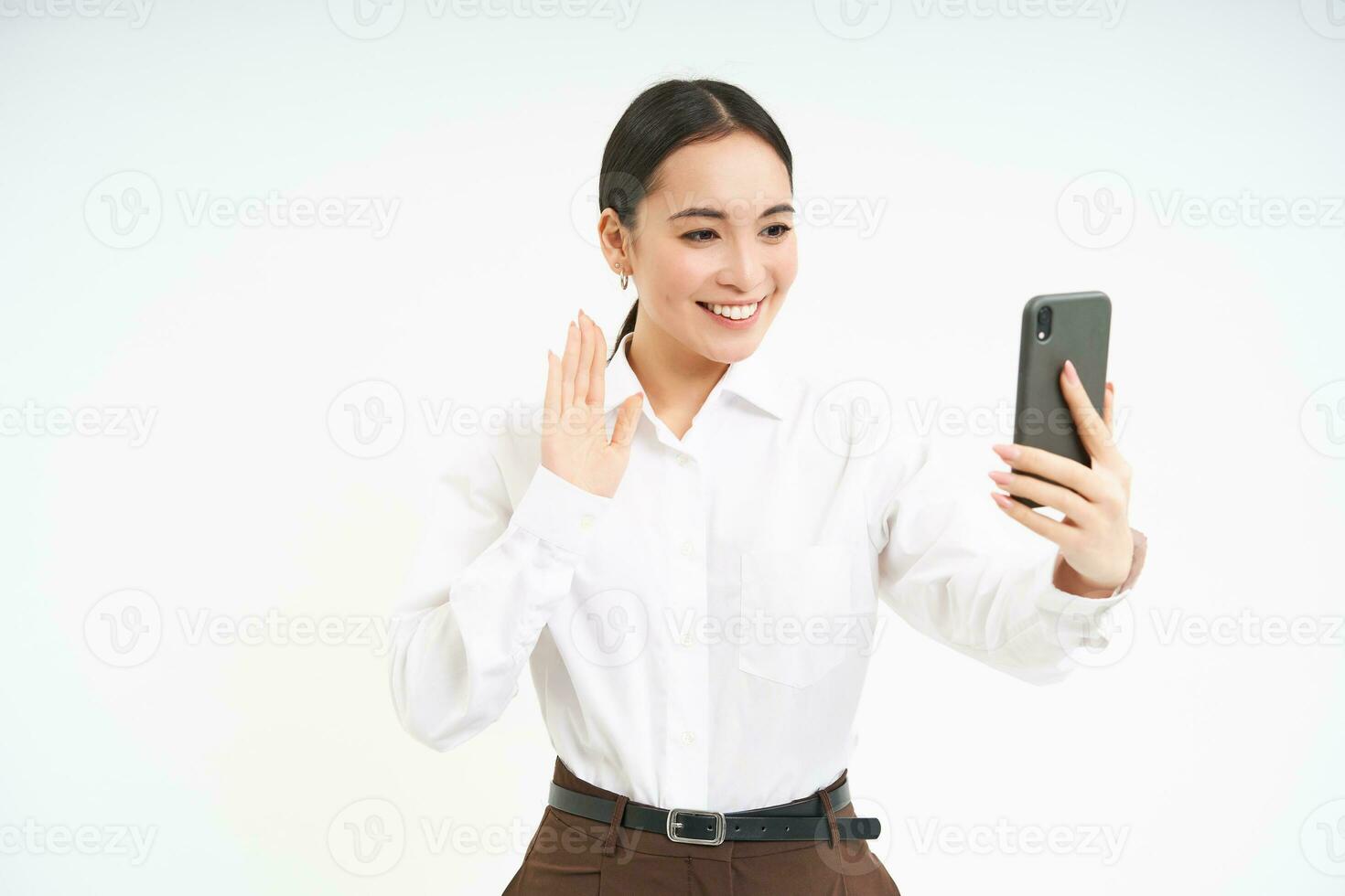 ritratto di aziendale donna, manager video chat su mobile Telefono, sembra a smartphone e conduce un' incontro in linea attraverso smartphone app, bianca sfondo foto