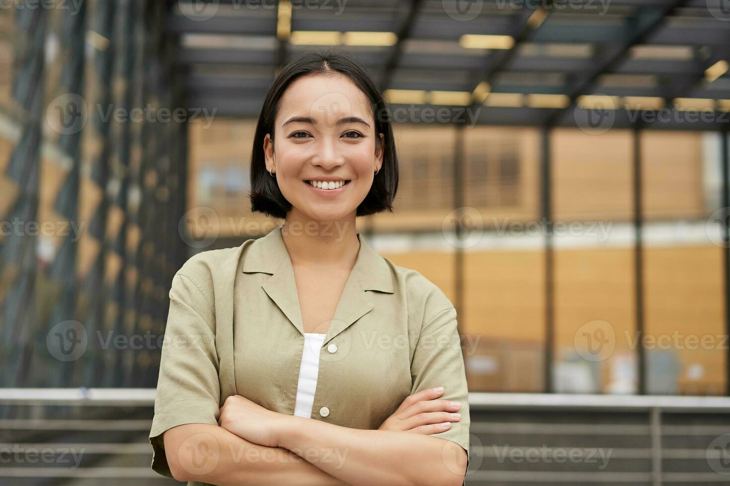 le persone. ritratto di fiducioso coreano ragazza, giovane alunno attraversare braccia su il petto, in piedi nel energia posa e sorridente a telecamera foto