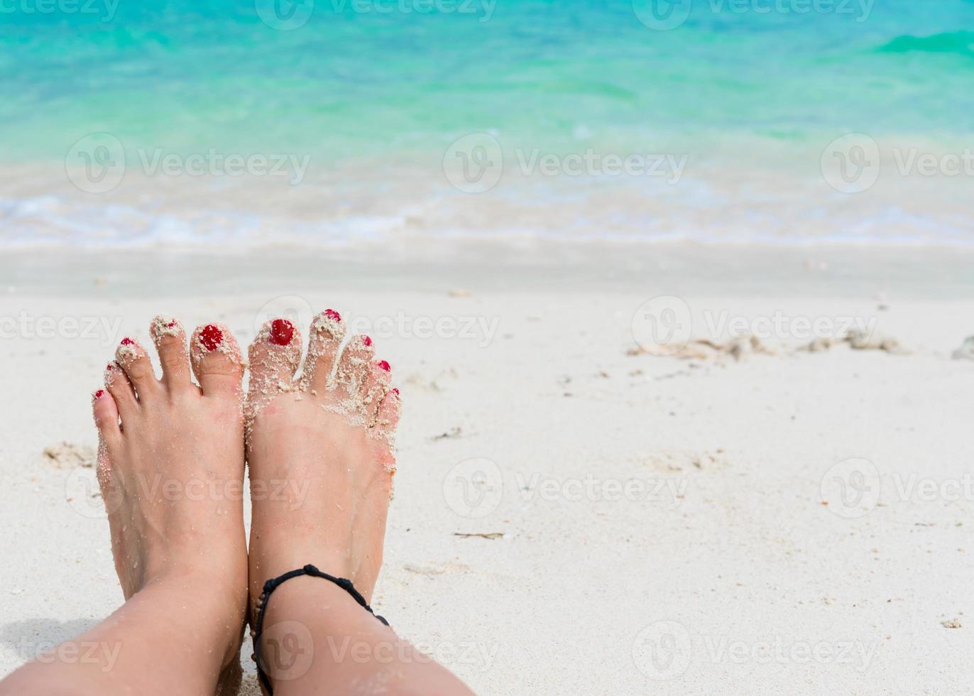 piedi di donna e unghie rosse sulla spiaggia foto