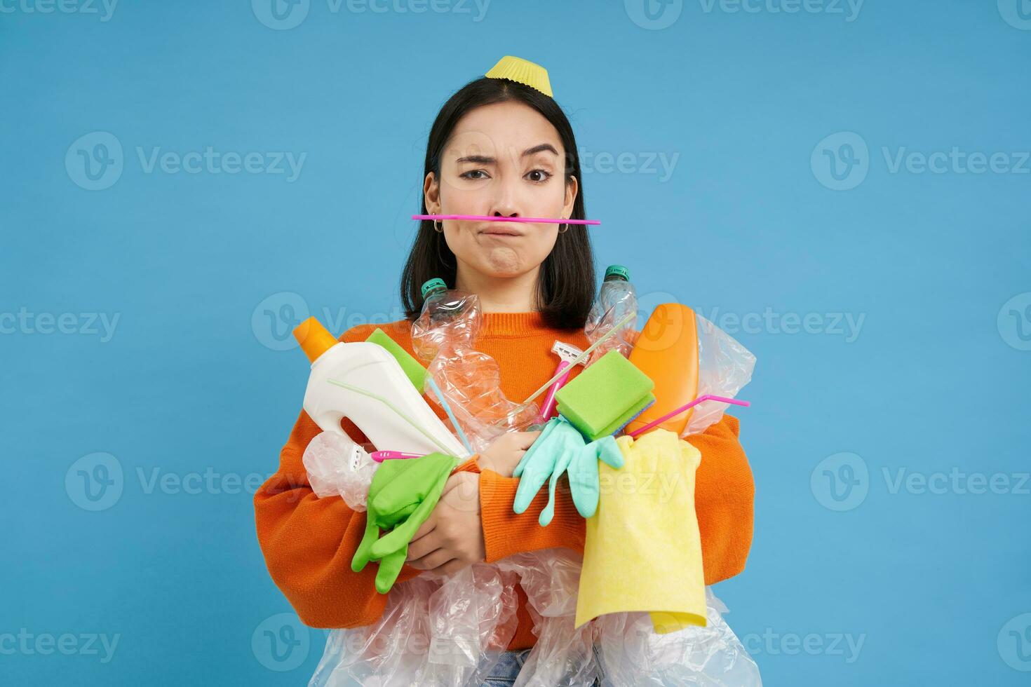 ambiente e ecologia. ritratto di asiatico donna Tenere plastica sciupare, mucchio di spazzatura, blu sfondo foto