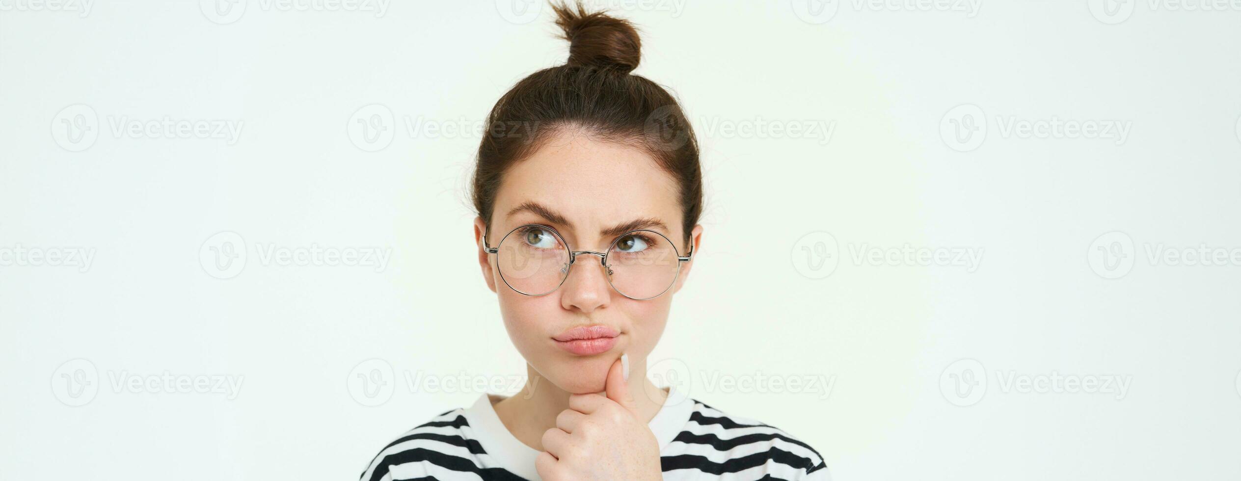 Immagine di donna nel occhiali, pensiero, meditando qualcosa, guardare lontano con riflessivo viso, analizzando, in piedi al di sopra di bianca sfondo foto