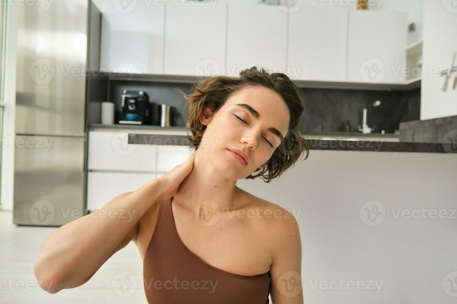 vicino su ritratto di sportiva, fitness donna massaggio sua collo, riscaldamento sua corpo dopo allenamento, fare yoga su gomma da cancellare stuoia a casa foto