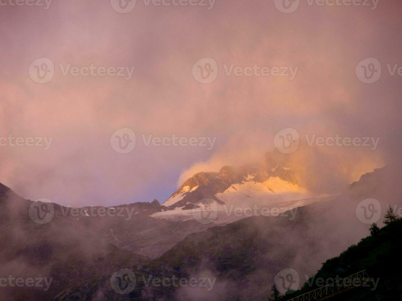 un' montagna con nuvole e un' leggero splendente su esso foto