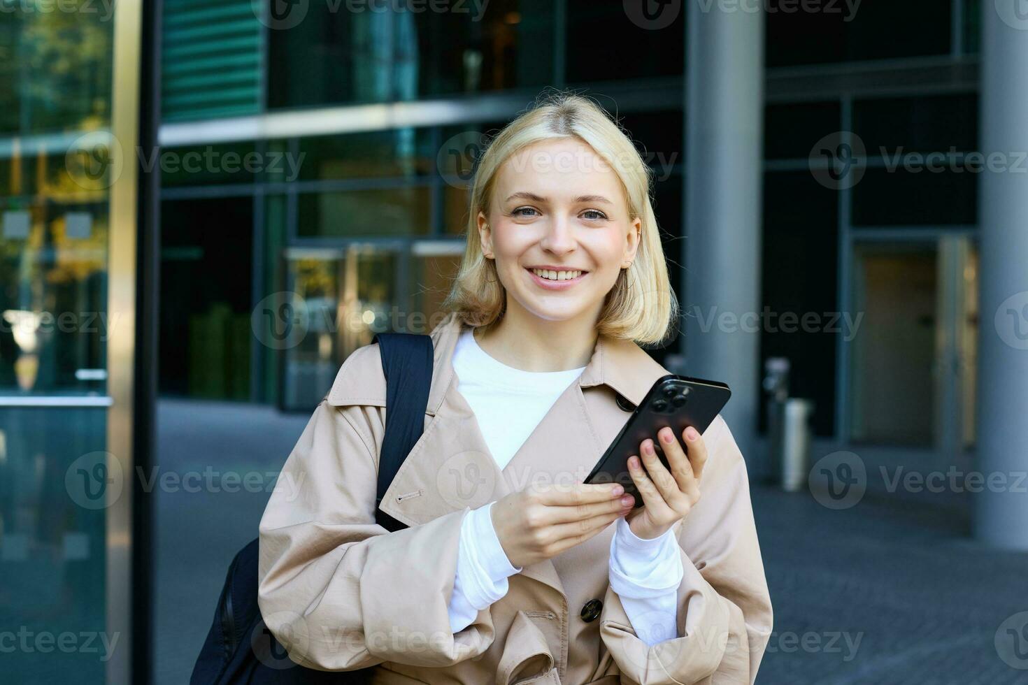 stile di vita ritratto di giovane bellissimo donna, in attesa per qualcuno su strada, Tenere smartphone, utilizzando mobile Telefono, ordinazione Taxi nel applicazione foto