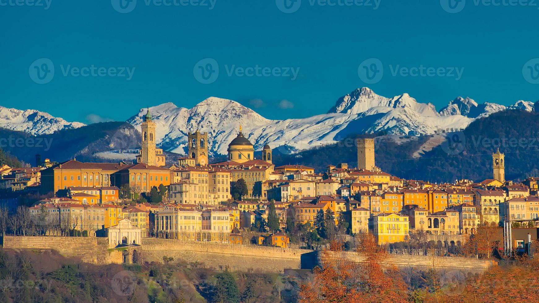 la città di bergamo con dietro le montagne bianche di neve foto