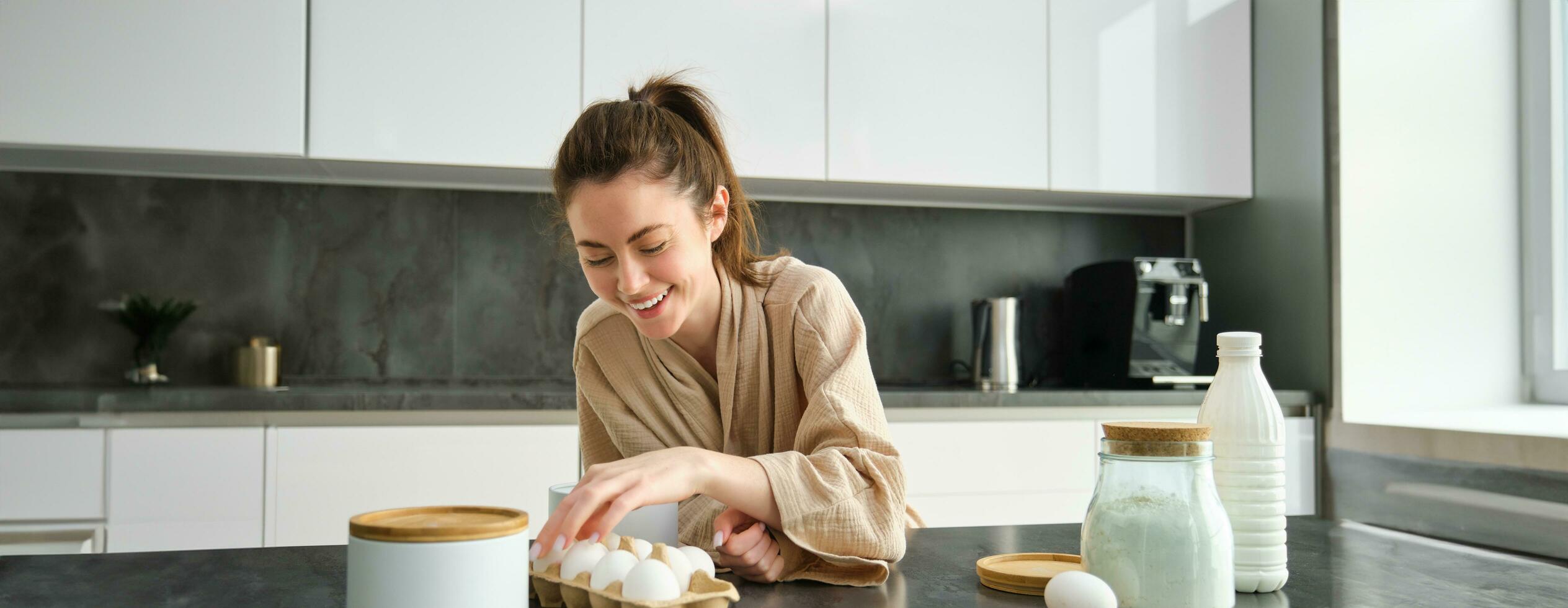 attraente giovane allegro ragazza cottura al forno a il cucina, fabbricazione Impasto, Tenere ricetta prenotare, avendo idee foto