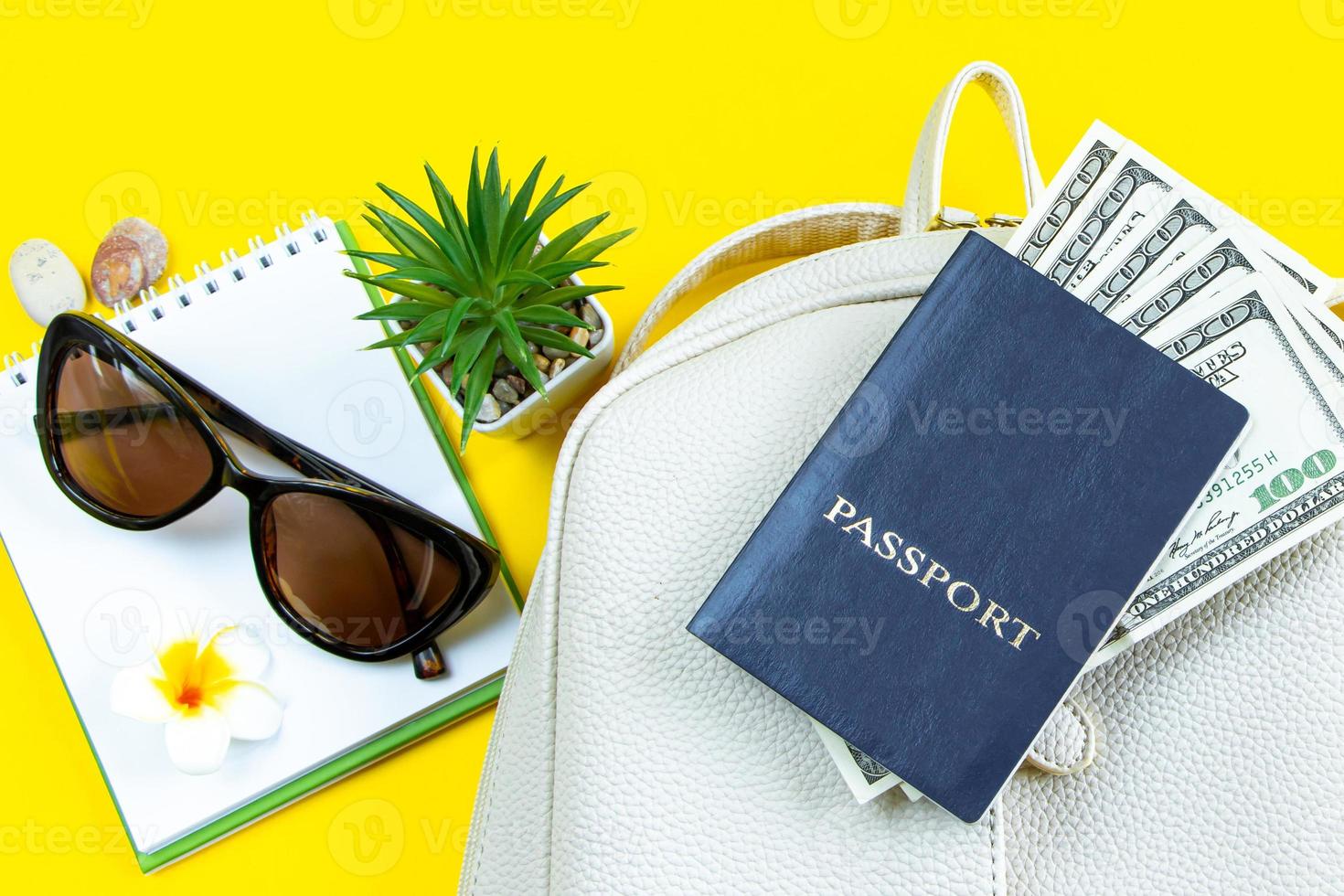 set di accessori alla moda per le tue vacanze estive. viaggio estivo. passaporto, occhiali da sole, zaino e denaro su sfondo giallo. foto