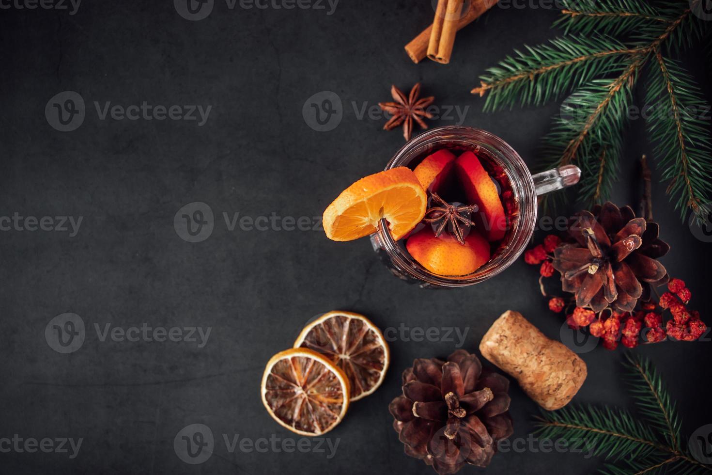 tradizionale vin brulè natalizio. bevanda calda con spezie in tazza di vetro su sfondo scuro. foto