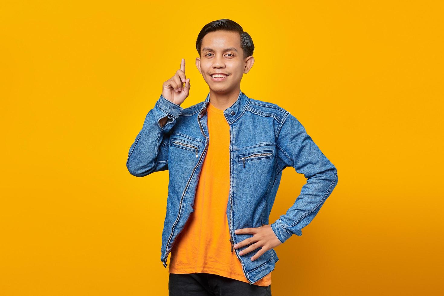 ritratto di allegro giovane uomo asiatico che punta alla promozione pubblicitaria dal vivo isolato su sfondo giallo foto