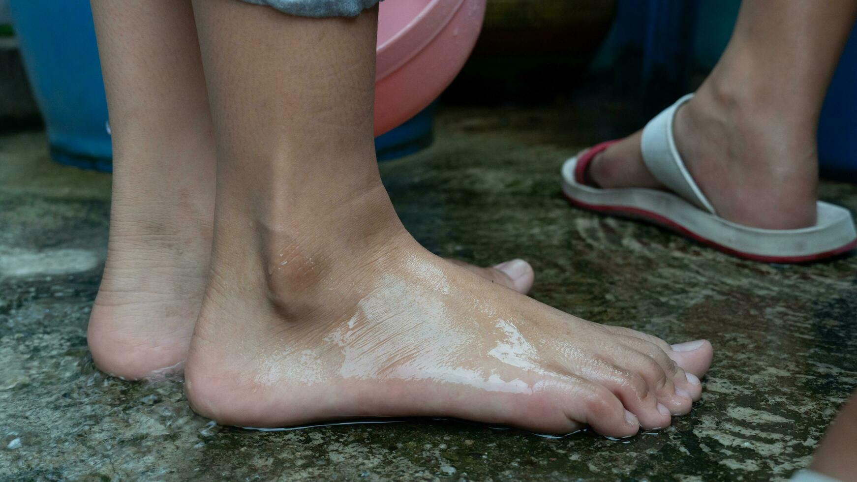 ragazza piedi bagnato a partire dal lavaggio piedi. un vecchio cemento pavimento quello era bagnato e a partire dal altro persone piedi. foto