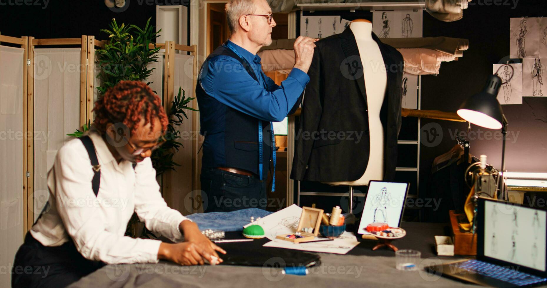 artigiano e allievo progettazione Abiti nel officina, Lavorando con sartoria tessuto per fatto a mano processi. Atelier apprendista apprendimento moda design abilità a partire dal esperto sarto. palmare sparo. foto