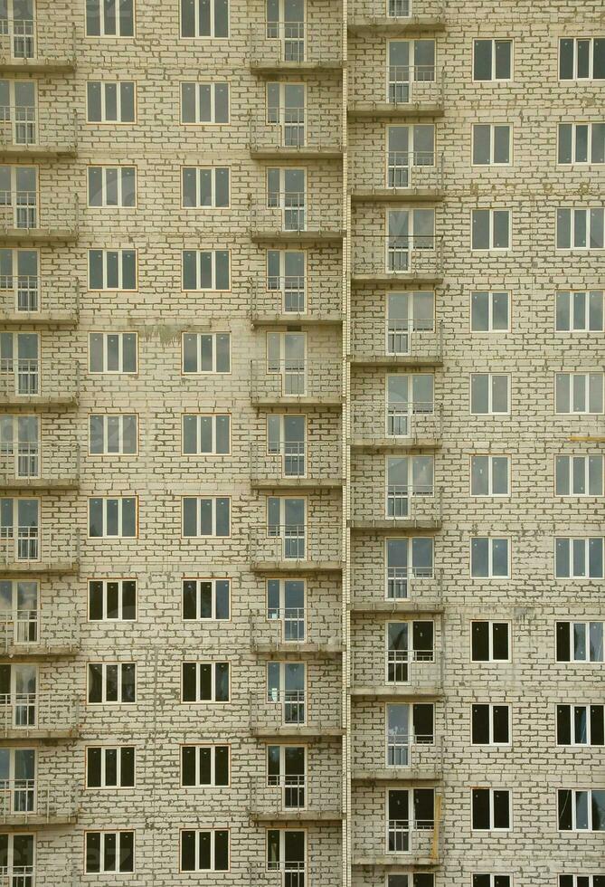 strutturato modello di un' russo pietra bianca Residenziale Casa edificio parete con molti finestre e balcone sotto costruzione foto