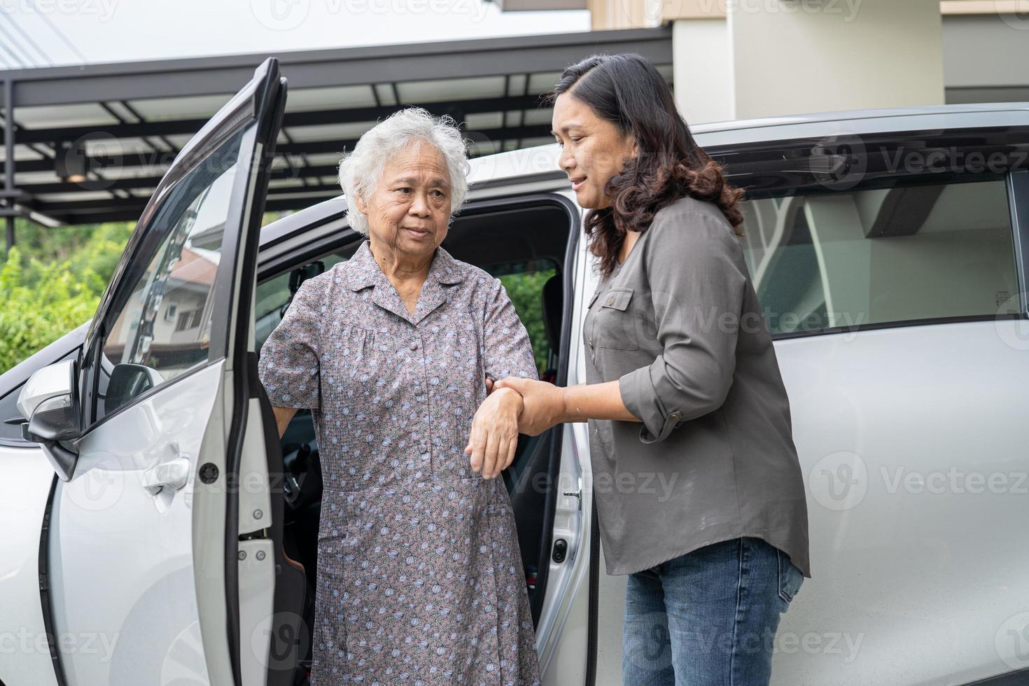 aiutare e supportare la donna anziana o anziana asiatica paziente seduta su sedia a rotelle prepararsi a raggiungere la sua auto, concetto medico sano e forte foto