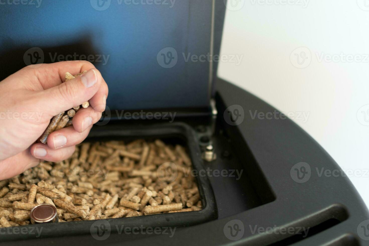 pellet fornello, uomo Tenere granuli nel il suo mano sopra un' moderno nero stufa foto