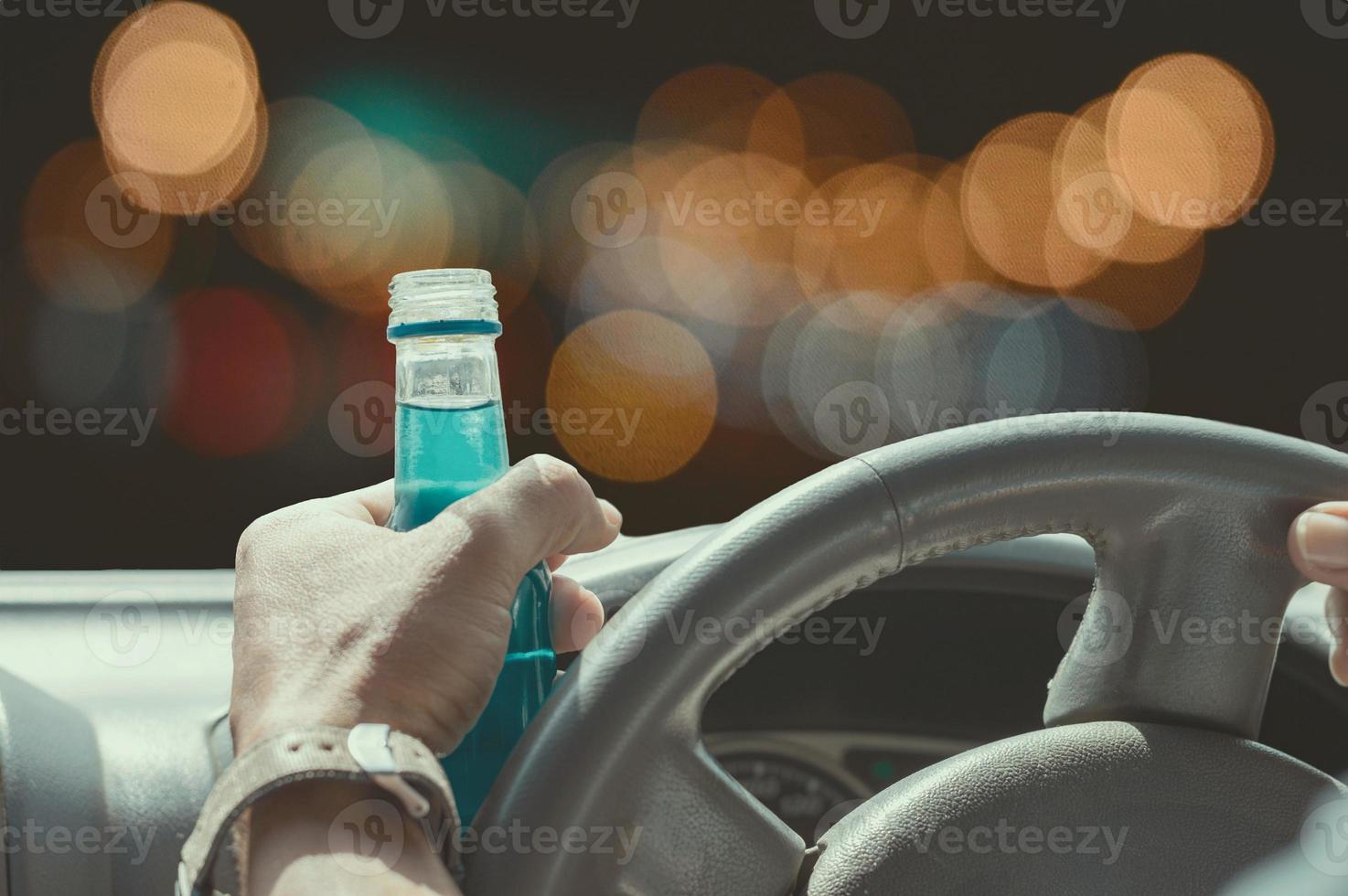 non bere e guidare il concetto, ubriaco e alla guida di un'auto con una bottiglia di alcol foto