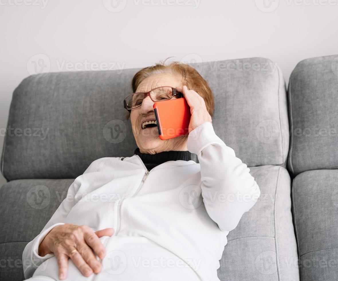 Miling senior donna che parla su smartphone a casa foto
