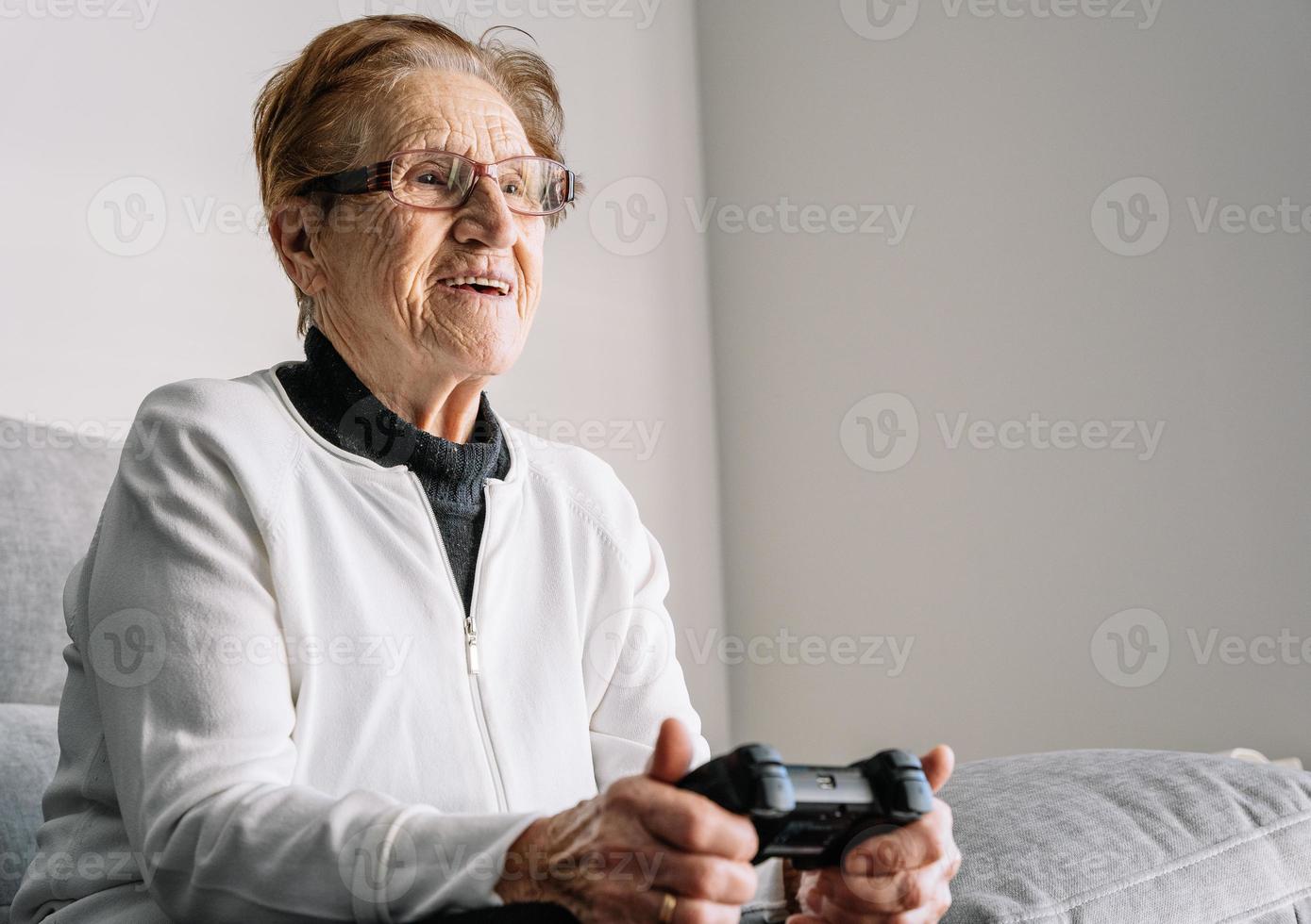 ritaglia una donna anziana con gamepad a casa foto