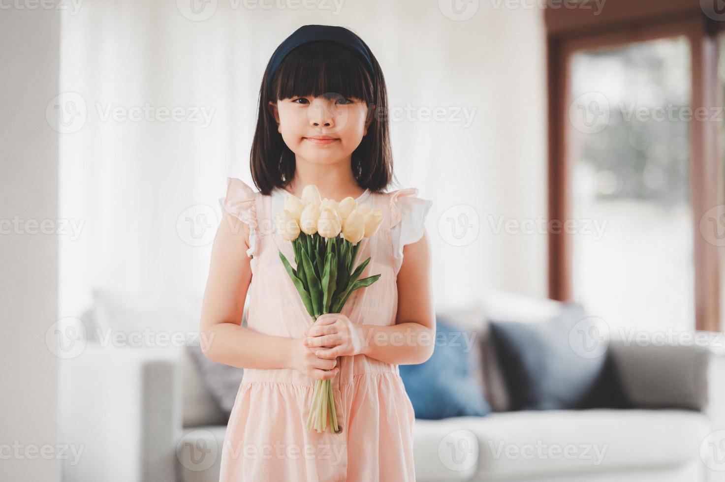 piccola figlia asiatica che tiene in mano un mazzo di fiori foto