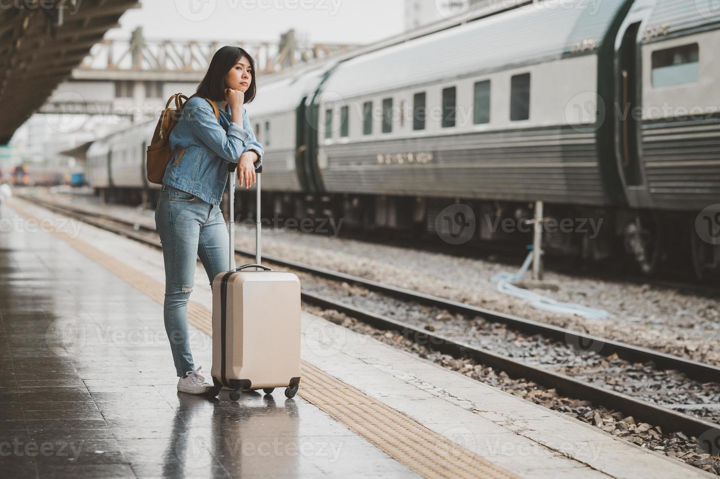 donna asiatica in attesa del treno alla piattaforma della stazione ferroviaria foto