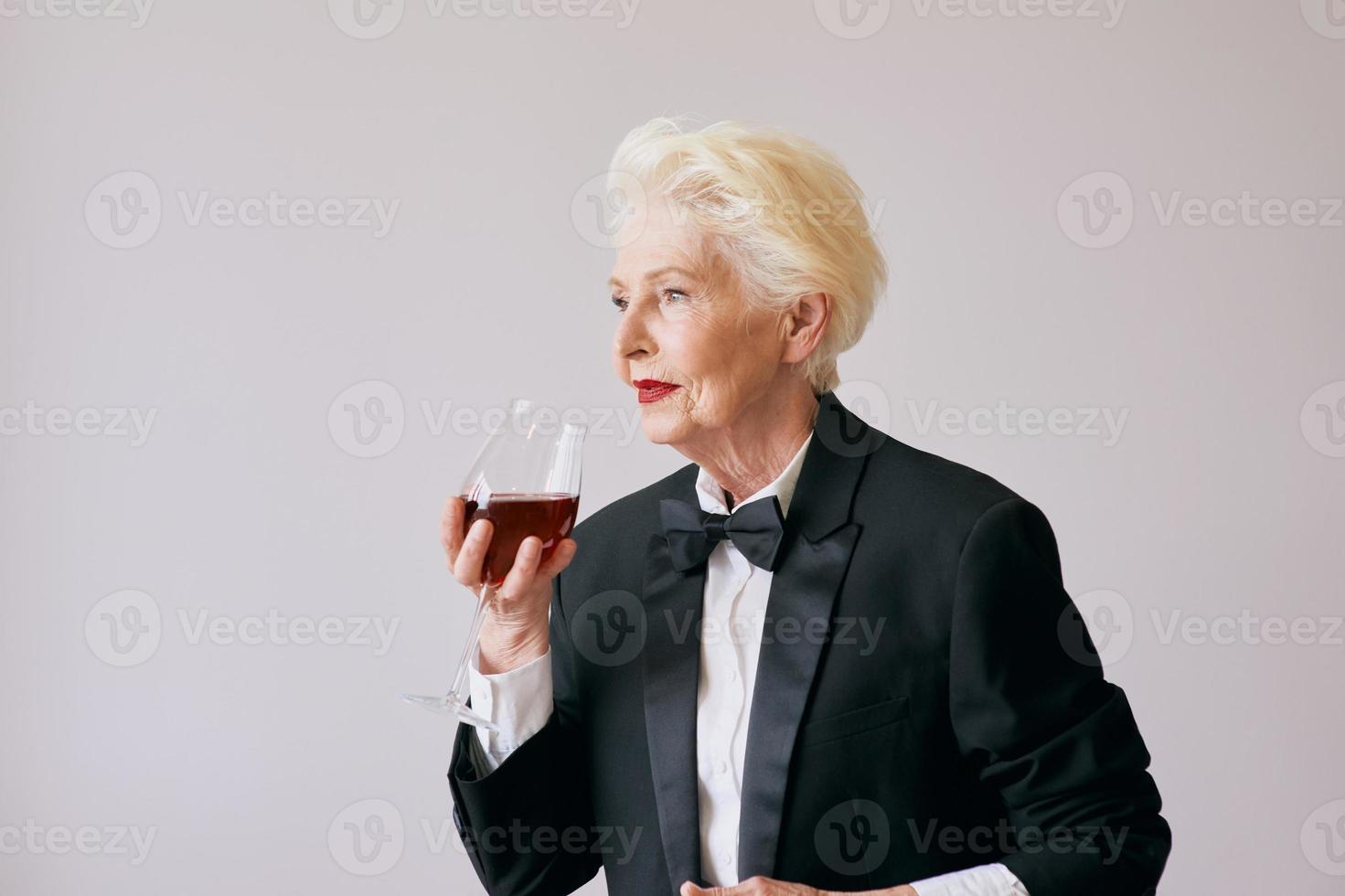 elegante donna sommelier senior in smoking con bicchiere o vino rosso. bevanda, maturo, concetto di stile foto