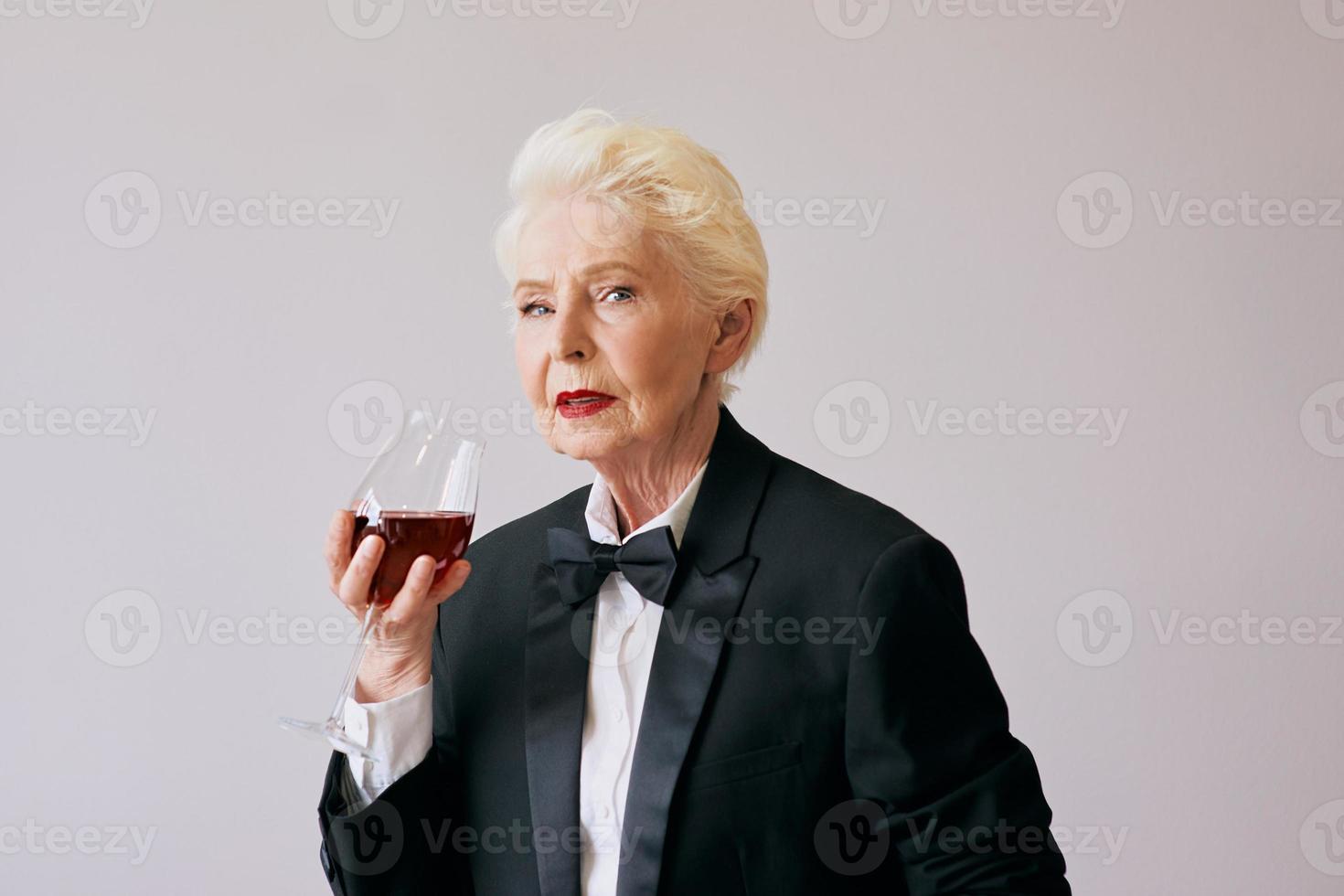 elegante donna sommelier senior in smoking con bicchiere o vino rosso. bevanda, maturo, concetto di stile foto