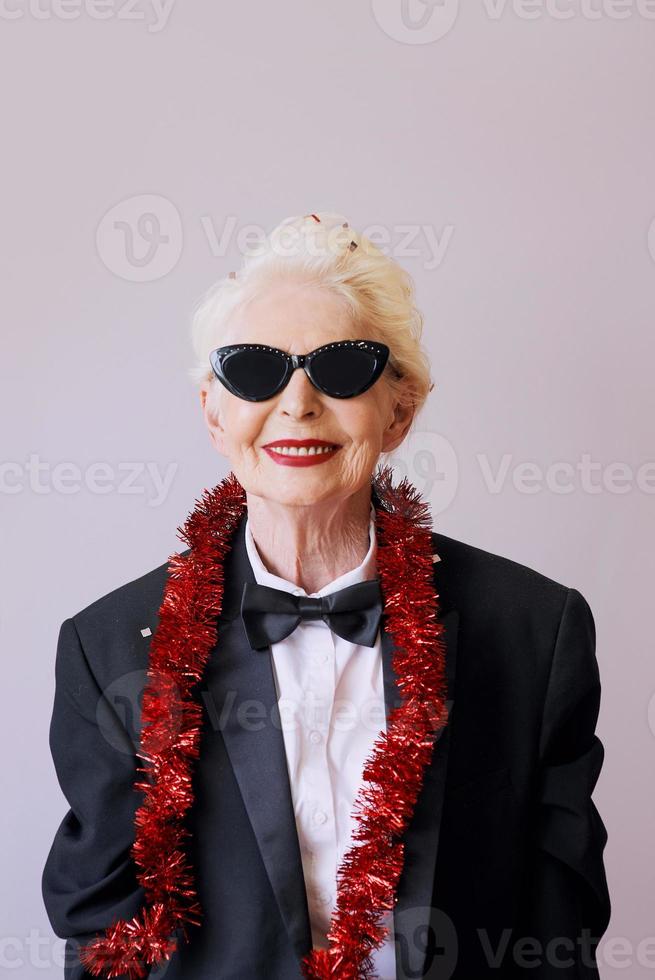 bella ed elegante donna anziana matura in occhiali da sole e smoking per celebrare il nuovo anno. divertimento, festa, stile, concetto di celebrazione foto