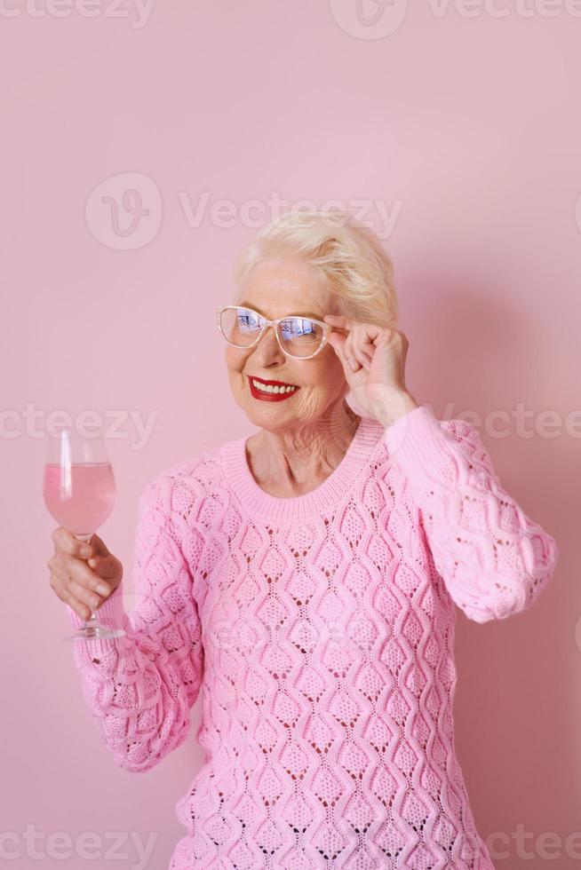 felice senior caucasica donna in cashmere maglione rosa bere rosa su sfondo rosa. celebrare, amore, pensione, concetto maturo foto