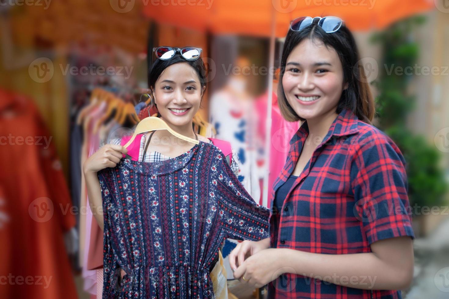 due sorridenti giovane donna asiatica con lo shopping e comprare all'aperto foto