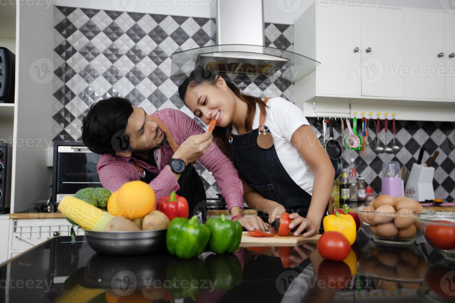 giovane coppia felice e sorridente che cucina cibo nella cucina di casa foto