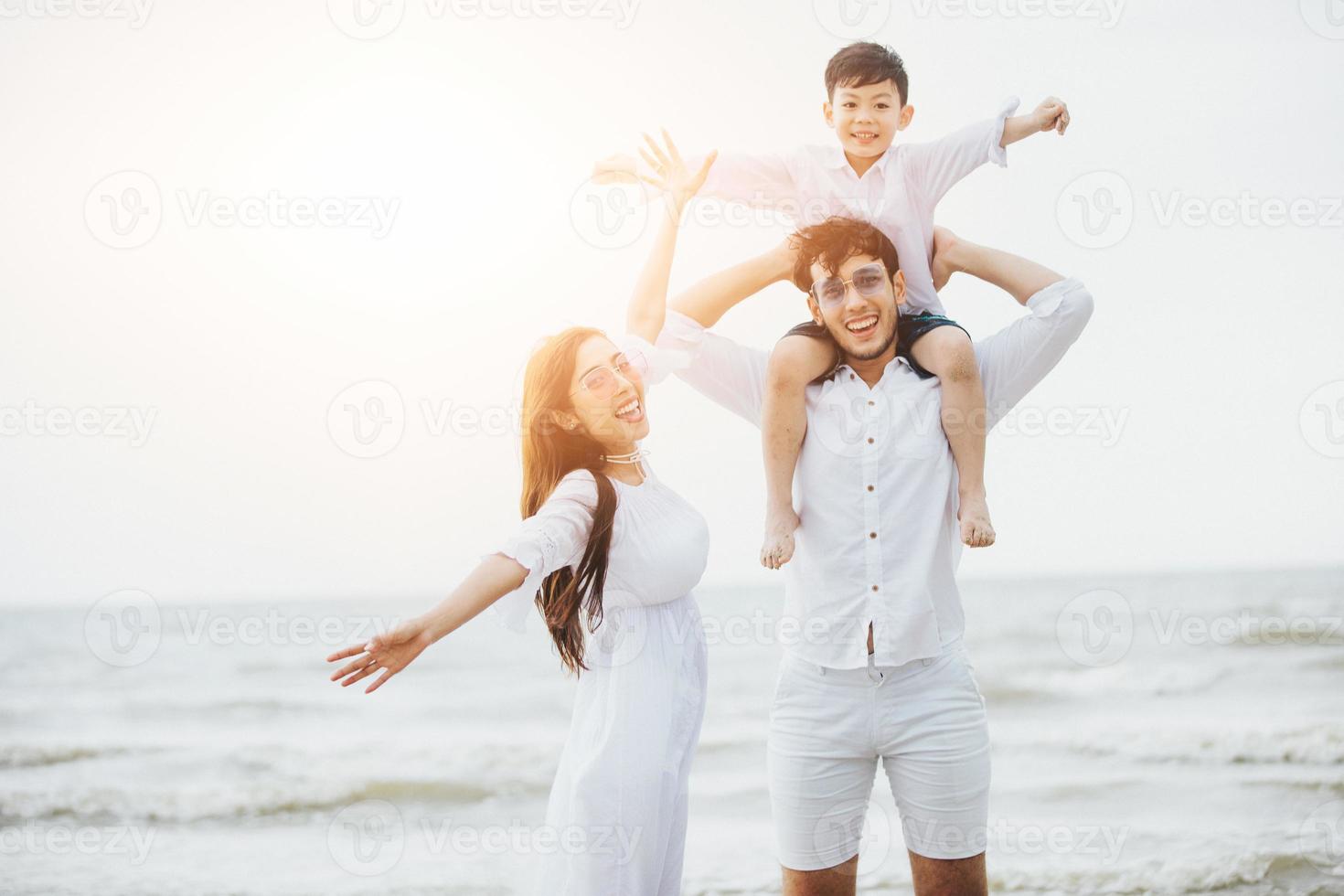 genitori attivi e persone attività all'aperto durante le vacanze estive e le vacanze con i bambini. La famiglia felice e il figlio camminano con il divertimento del mare al tramonto sulla spiaggia di sabbia. foto