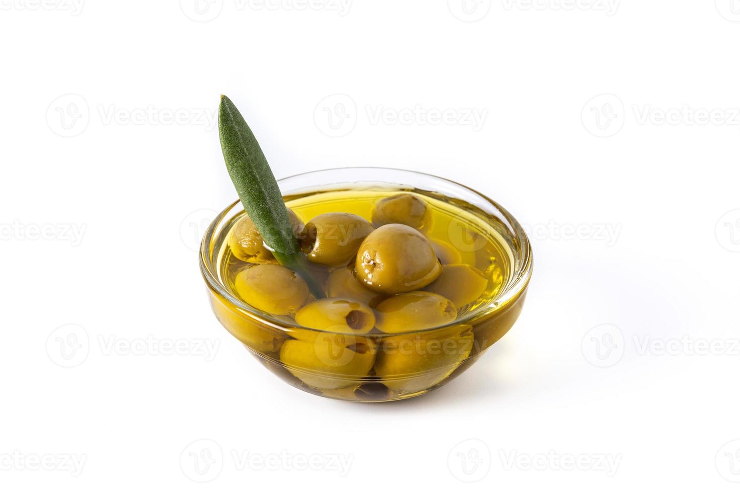 olio d'oliva vergine con olive verdi in ciotola di cristallo isolato su sfondo bianco foto