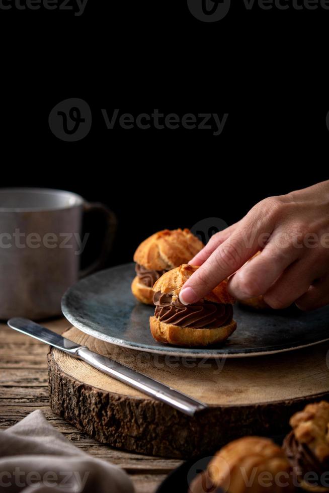 Deliziosi profiteroles su tavola in legno rustico foto