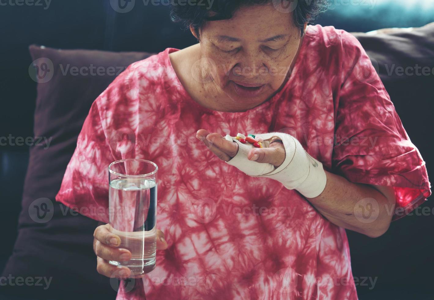 la donna asiatica anziana prende la medicina della pillola a portata di mano? foto