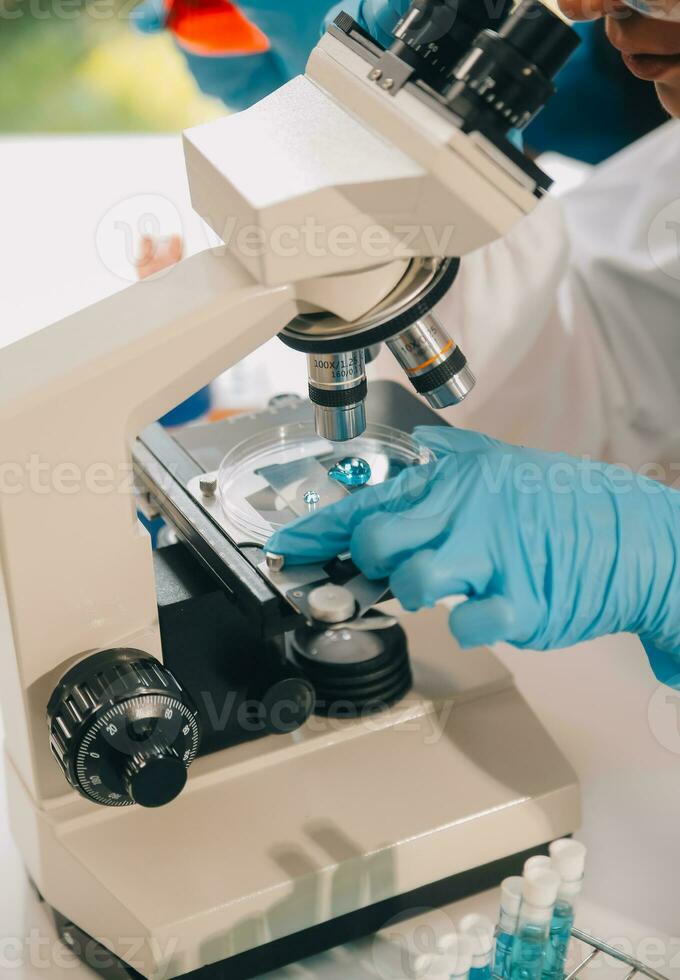 team di ricercatori biochimici che lavora con il microscopio per lo sviluppo del vaccino contro il coronavirus nella ricerca farmaceutica labolatoria, messa a fuoco selettiva foto