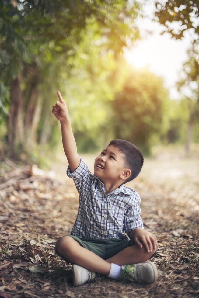 felice ragazzo seduto e pensare da solo nel parco foto