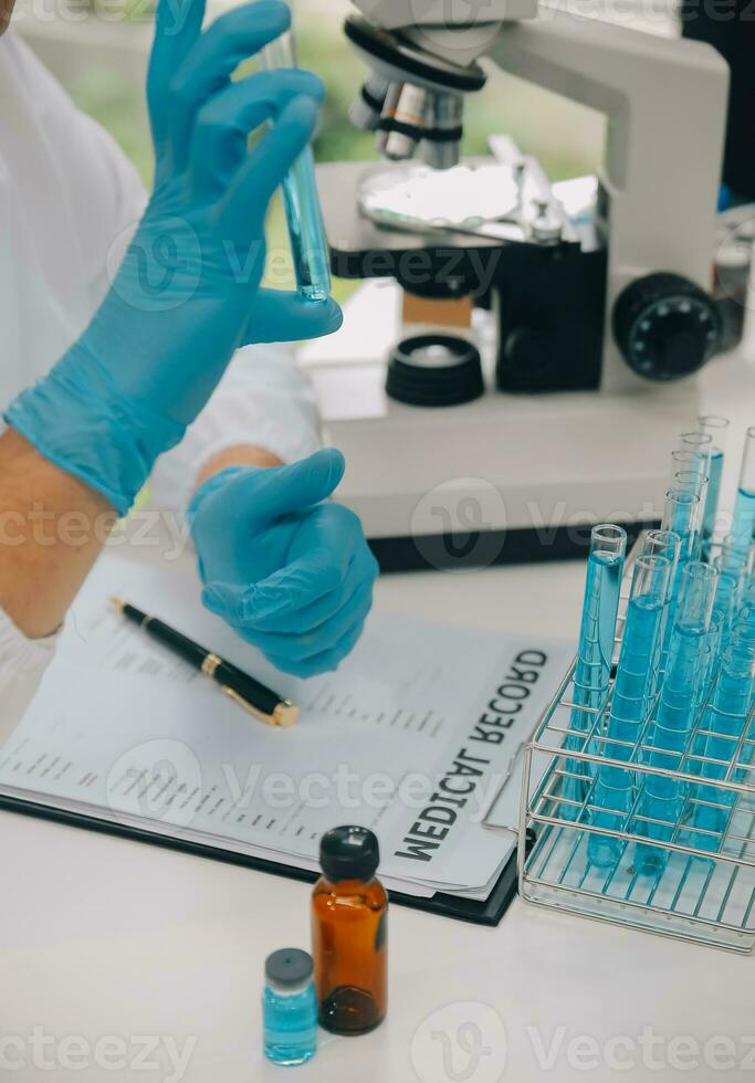 scienziato o medico nel laboratorio cappotto Lavorando nel biotecnologico laboratorio, microscopio attrezzatura per ricerca con miscelazione reagenti nel bicchiere borraccia nel clinico laboratorio. foto