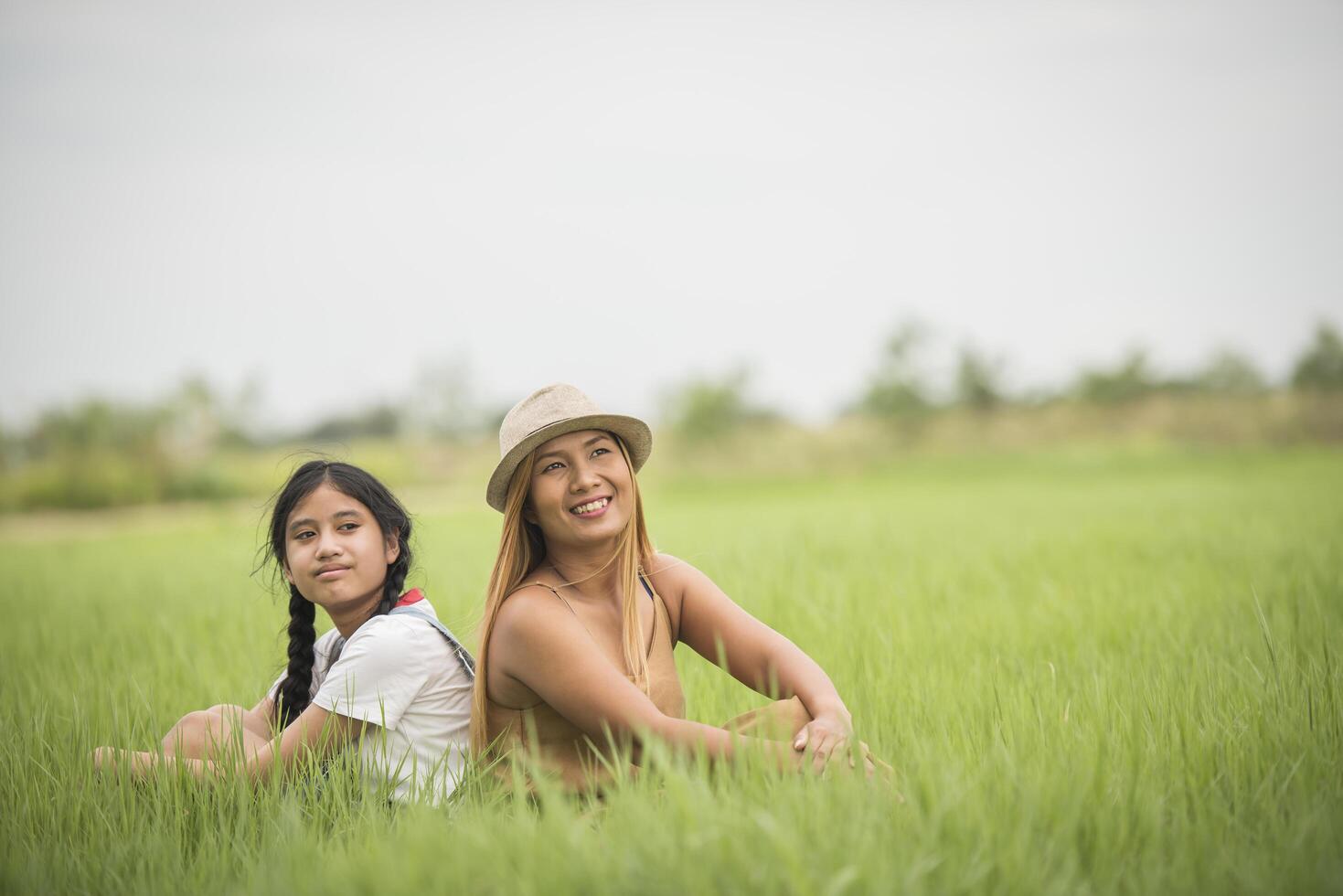 madre felice con la figlia che si siede sul parco del campo di erba foto