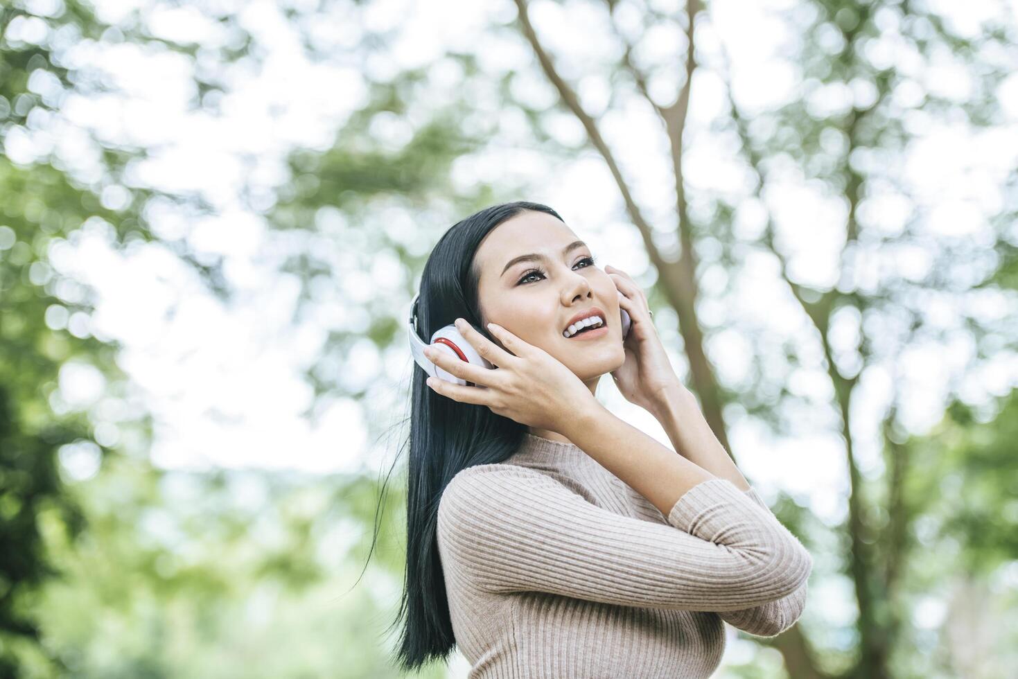 donna asiatica che ascolta la musica preferita sulle cuffie. tempo felice e relax. foto