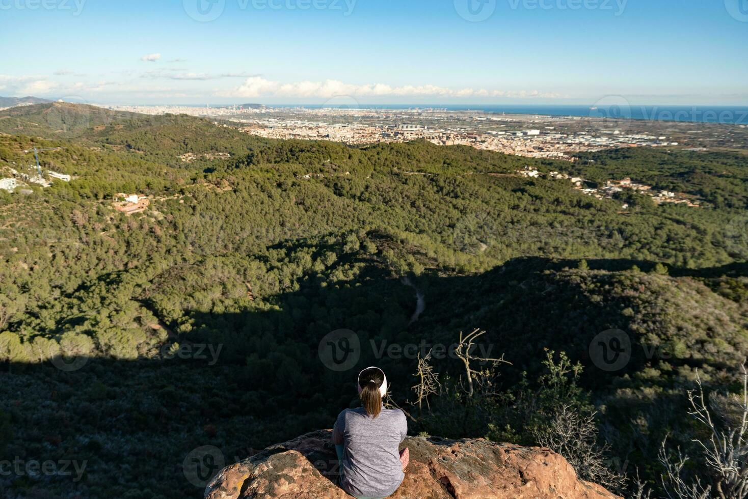 rilassato donna seduta su superiore di un' montagna contemplando il paesaggio. foto