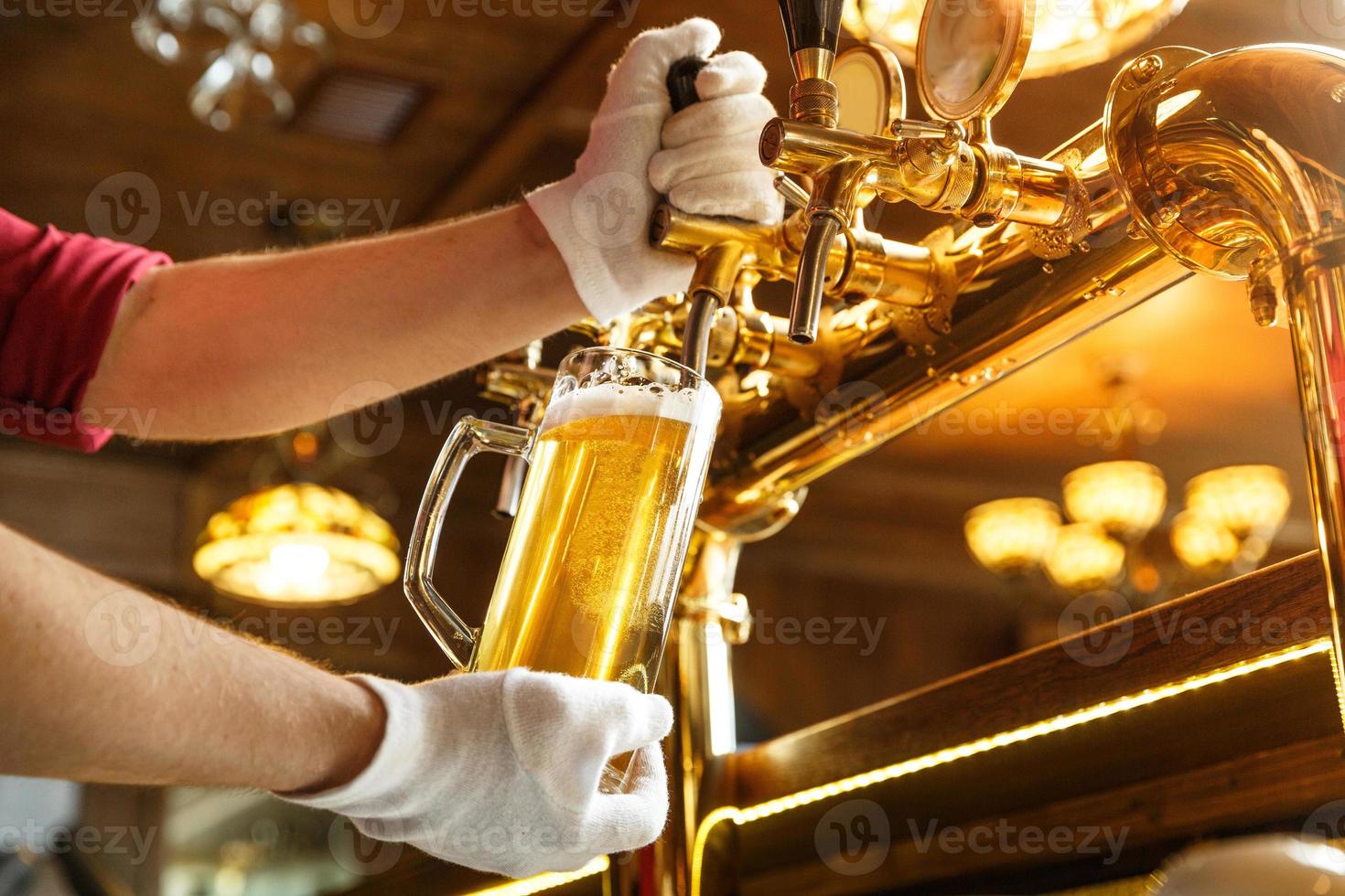 mani del barista che versano birra leggera in un bicchiere foto