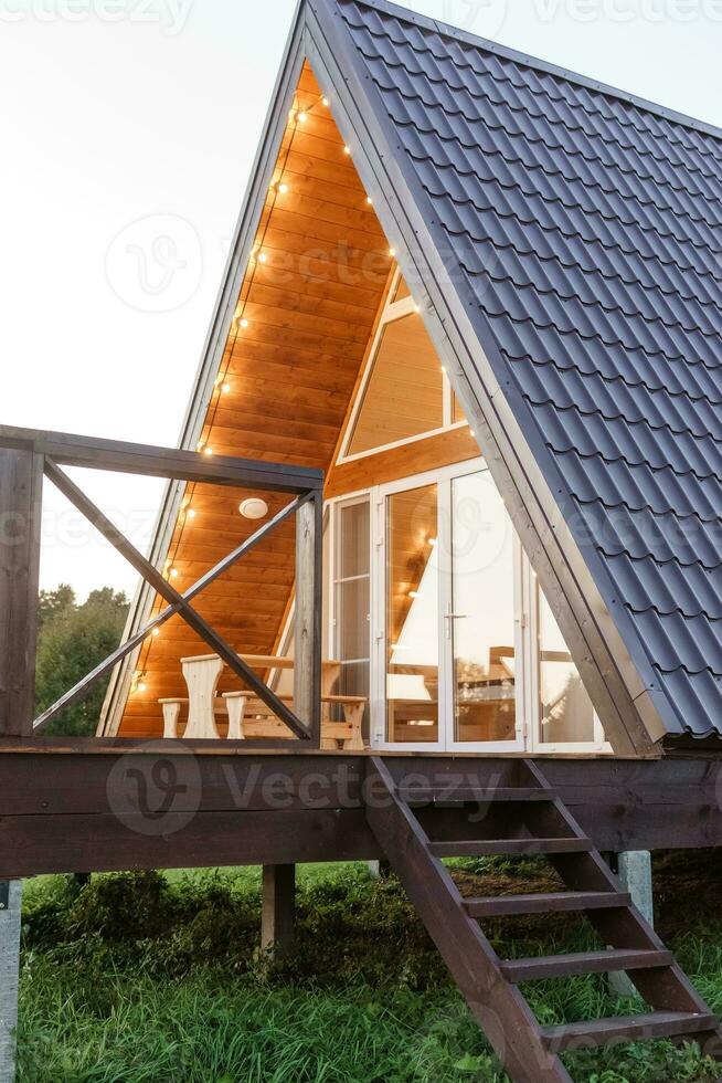 il concetto di glamping e Noleggio un' chalet per fine settimana. di legno Casa con un' veranda nel natura in giro conifero alberi foto